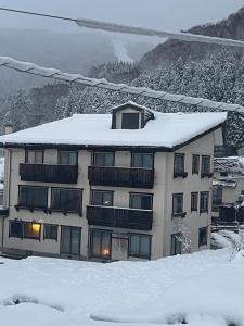 a building with snow on top of it at Lodge Seizan in Nozawa Onsen