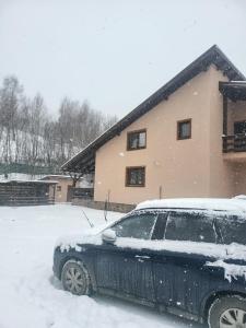une voiture garée dans la neige devant une maison dans l'établissement Vila Andrei, à Zărneşti