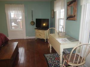 a living room with a tv and a desk with a table at Grand Oak Manor Bed and Breakfast in Granville Ferry