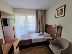 a hotel room with a bed and a chair at Hotel Ostaniec in Kroczyce