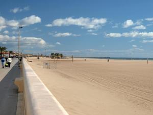 a sandy beach with people walking on the beach at Joli appartement avec vue mer in Narbonne