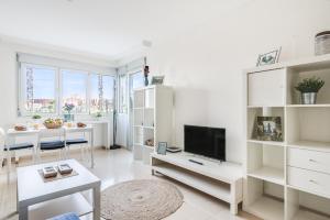 a white living room with a tv and a table at Home2Book Comfy Apartment Rambla in Las Palmas de Gran Canaria