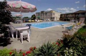 uma piscina com uma mesa e um guarda-sol em Days Inn by Wyndham Brockville em Brockville