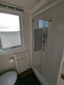 a bathroom with a shower and a toilet and a window at Sleeps 6 Modern and bright Caravan Littlesea Haven Weymouth in Weymouth