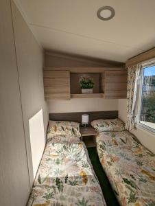 Habitación pequeña con 2 camas y ventana en Sleeps 6 Modern and bright Caravan Littlesea Haven Weymouth, en Weymouth