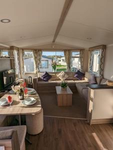 Wohnzimmer eines Campers mit Sofas und Tischen in der Unterkunft Sleeps 6 Modern and bright Caravan Littlesea Haven Weymouth in Weymouth