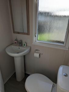 a bathroom with a sink and a toilet and a window at Sleeps 6 Modern and bright Caravan Littlesea Haven Weymouth in Weymouth