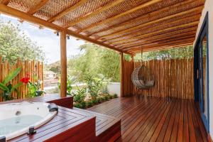 Pousada Alto da Pipa في بيبا: سطح خشبي مع حوض استحمام وأرجوحة