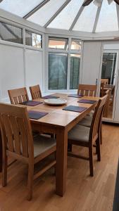 uma mesa de jantar em madeira com cadeiras e um telhado de vidro em Cosy relaxing 4 bed Home with 2 parking Space em Hatch End