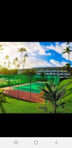 una valla con una palmera delante de un edificio en Ancorar flat resort- porto de galinhas, en Porto de Galinhas