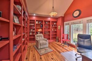 una biblioteca con paredes rojas, una silla y un reloj en Spacious Statesboro House with Private Pool!, en Statesboro