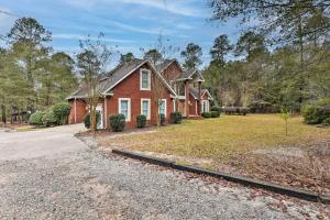 a red brick house in a yard with a driveway at Spacious Statesboro House with Private Pool! in Statesboro