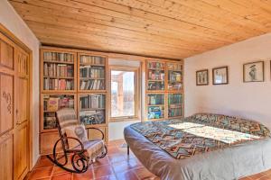 El Prado的住宿－Southwest Home with 360-Degree Mtn View, Ski Nearby!，一间卧室配有床、椅子和书架
