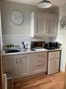 una cocina con armarios blancos y un reloj en la pared en 'Little Acre' perfect for business or pleasure, en Portadown