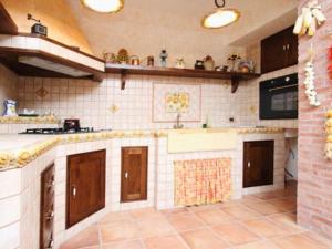cocina con armarios marrones y suelo de baldosa en Holiday home in Francavilla di Sicilia, en Francavilla di Sicilia