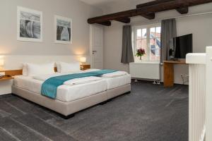 1 dormitorio con 1 cama grande y TV en Schiefer Suite Hotel & Apartments, en Goslar