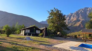 una casa con parque infantil frente a una montaña en Cabañas Emporio de la Meme en San José de Maipo