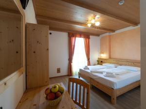 Un dormitorio con una cama y una mesa con un bol de fruta en Agritur Sandro en Sporminore
