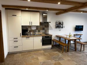 a kitchen with white cabinets and a wooden table at Thallerhof in Griesstätt