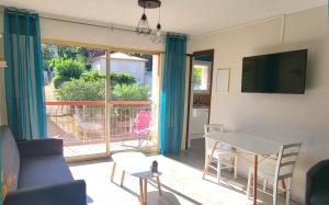 a living room with a table and a view of a balcony at Le Bel Air - Central avec Climatisation & Parking in Gréoux-les-Bains