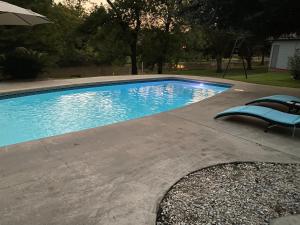 a swimming pool with a chair and an umbrella at Cajun-Get Away in Breaux Bridge