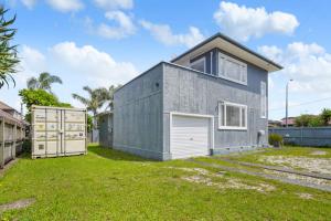 uma casa cinzenta com uma garagem num quintal em Amazing Home By Beach - Fully Aircon-ed - Wifi em Auckland