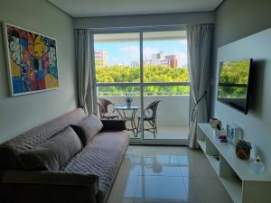 a living room with a couch and a large window at EXCELENTE FLAT 2 QUARTOS no BESSA in João Pessoa