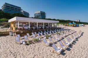 a bunch of chairs on a beach with a building at WAVE private apartment - Fancy Sunset in Międzyzdroje