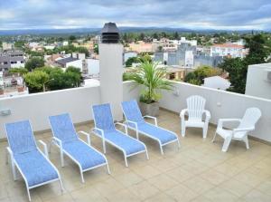 Un balcón con sillas azules y blancas y vistas. en Departamento centrico Villa Carlos Paz en Villa Carlos Paz