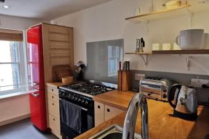 een keuken met een fornuis en een rode koelkast bij Spacious 2 Bedroom Apartment in the heart of Soho. in Londen