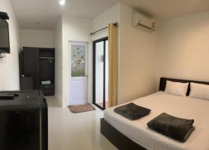 a bedroom with a bed and a television and a door at Golf House in Ban Bang Phai