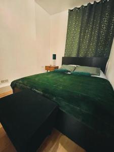 a bedroom with a large green bed with a table at London Luxury Apartment with Private Jacuzzi Hot tub & Sauna in London