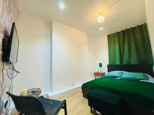 a bedroom with a green bed and a chair at London Luxury Apartment with Private Jacuzzi Hot tub & Sauna in London