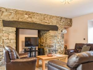 a living room with leather chairs and a stone fireplace at Woodland Cottage in Pont Yates