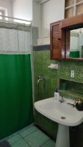 Un baño con lavabo y ducha verde. en Hostal Cotroneo, en Viña del Mar 100 fotos más