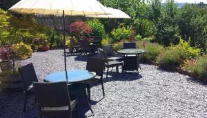 eine Terrasse mit Tischen, Stühlen und einem Sonnenschirm in der Unterkunft Dunkery Beacon Country House in Wootton Courtenay