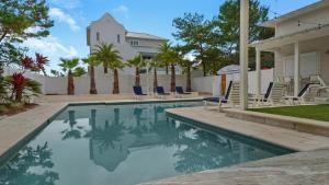una piscina con sillas y una casa en Emotional Rescue, en Inlet Beach