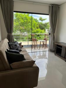 a living room with a couch and a balcony at Ap Praia de Taperapuan Porto Seg in Porto Seguro