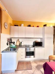 cocina con armarios blancos, fregadero y microondas en Casa Unica- da Bruno en Colico