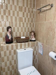 a bathroom with a toilet and two statues on a wall at "The Italian" Seafront Apartment in Eastbourne