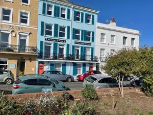a blue building with cars parked in a parking lot at "The Italian" Seafront Apartment in Eastbourne