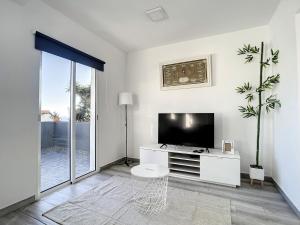 een witte woonkamer met een flatscreen-tv bij Casa da Avo by Atlantic Holiday in Caniçal