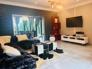 a living room with a couch and a tv at KwaSiya Guest House in Nelspruit