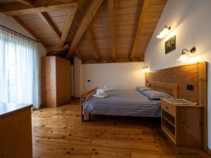 sypialnia z łóżkiem i drewnianą podłogą w obiekcie Agritur Widmann w mieście Coredo