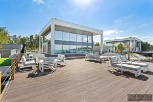 a deck with white lounge chairs and a building at WelHome - Extraordinary Giant Water Villa on Nurai Island in Abu Dhabi