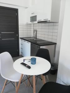 a small kitchen with a white table and chairs at Aiolos Blu Luxury Apartments in Nea Roda