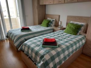 Casa da Sardinha في فوزيتا: سريرين في غرفة نوم مع وسائد خضراء وأحمر