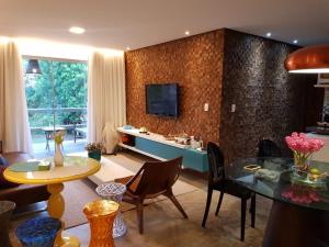uma sala de estar com uma mesa e uma televisão na parede em Villas do Pratagy resort Maceió próximo praia em Maceió