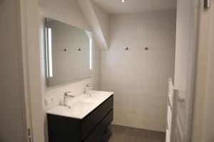 a white bathroom with a sink and a mirror at Luxe en comfortabel appartement aan het water in Kamperland +39 photos