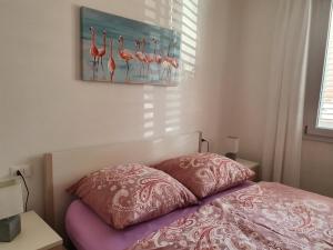 ein Bett mit zwei Kissen und einem Flamingos-Gemälde in der Unterkunft Gemütliche neue Ferienwohnung in La Ciaccia in Codaruina